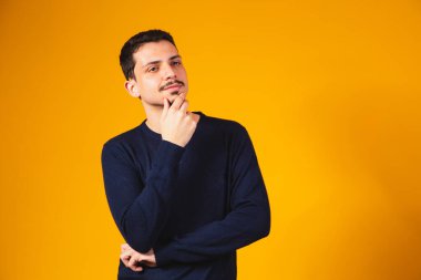 Sarı arka planda düşünceli bir öğrenci. Genç adam düşünüyor ve bir fikri var.