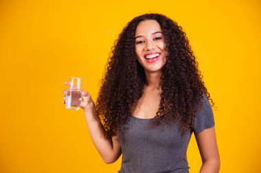 Sarı arka planda su içen güzel afro kadın. Mesaj için yer var..