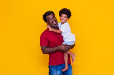 Baba ve afro oğul sarı arka planda gülümsüyor. Babalar Günü Konsepti