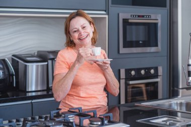 Yaşlı bir kadın uyandığında mutfakta çay ya da kahve içiyor..