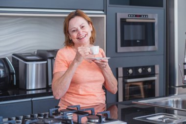 Yaşlı bir kadın uyandığında mutfakta çay ya da kahve içiyor..