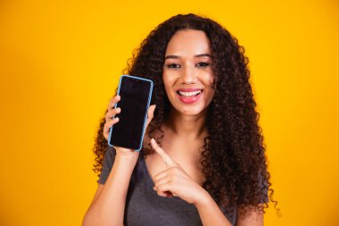 Tavsiye ederim. Şaşırmış Afrikalı Amerikalı kız boş telefon ekranını işaret ediyor. Boşluğu kopyala