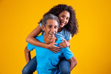 Mutlu kız babasının sırtında, sarı arka planda..