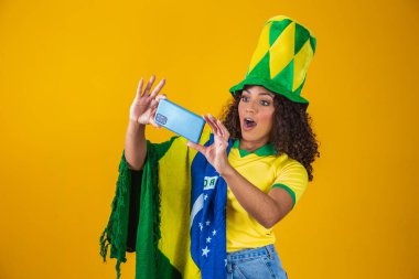 Brezilya futbol takımının destekçisi bir golü akıllı telefonu izleyerek kutluyor.
