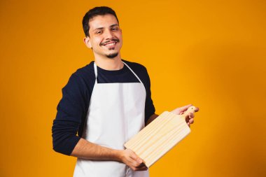 Elinde doğrama tahtası tutan beyaz önlüklü bir adam..