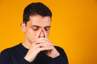 Gergin çocuk sarı arka planda dua ediyor. Tanrı 'yla konuşan sıkıntılı çocuk.