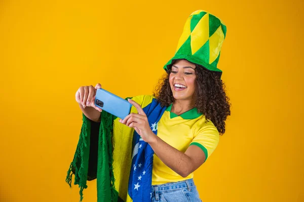 スマートフォンを見て目標を祝うブラジルのサッカーチームのサポーター — ストック写真