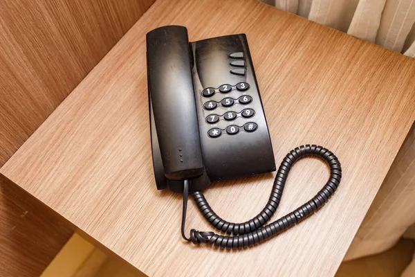 ホテルの茶色のテーブルの上に黒いヴィンテージの電話 — ストック写真