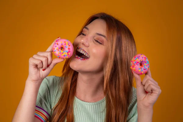Chica Pelirroja Sobre Fondo Amarillo Comiendo Deliciosas Rosquillas Coloridas — Foto de Stock