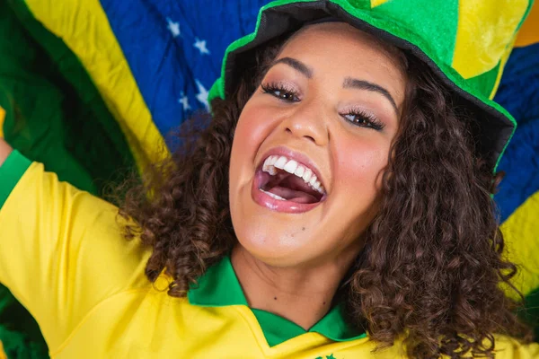 アフロの女の子は好きなブラジルのチームのために応援し 黄色の背景に国旗を保持 — ストック写真