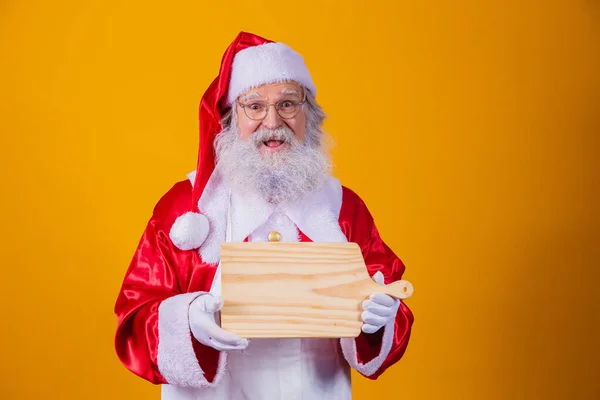 Noel Baba Önlük Giyip Sarı Arka Planda Boş Tahtası Tutuyor — Stok fotoğraf
