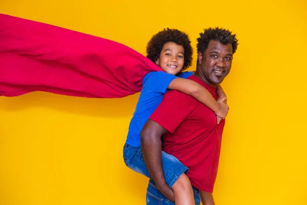 当時はアフリカ系の父と息子がスーパーヒーローを演じていた 黄色の背景が楽しい人 友好的な家族の概念 — ストック写真