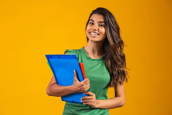 Sarı Arka Planda Elinde Okul Kitaplarıyla Gülümseyen Kadın Öğrenci — Stok fotoğraf