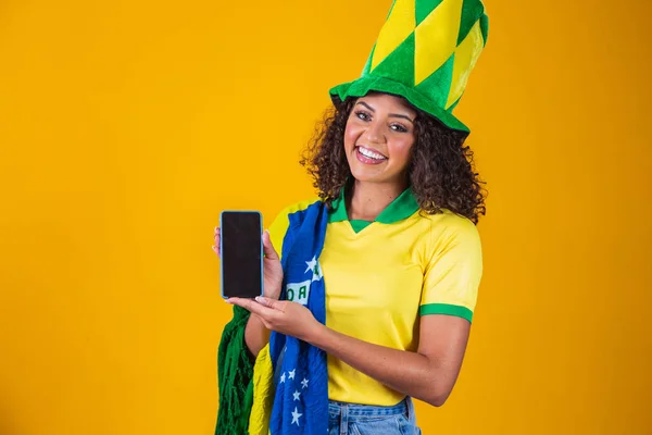 ブラジルのファンはコピースペース付きのスマートフォンを持っています 携帯電話を持つブラジルの女性サポーターテキストを書くための白い画面で — ストック写真