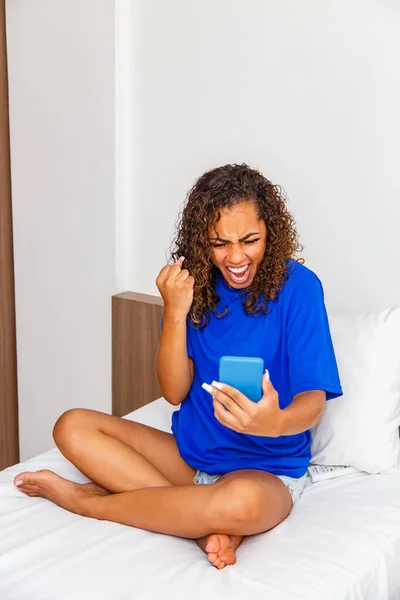 Mujer Joven Dormitorio Usando Teléfono Celular Celebrando —  Fotos de Stock