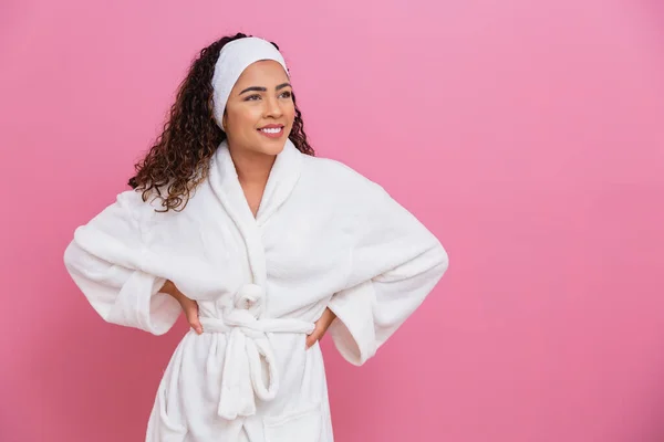 白いバスローブを着た美しいアフロの女の子テキストのためのスペースとピンクの背景にサッシ 健康とケアの概念 — ストック写真