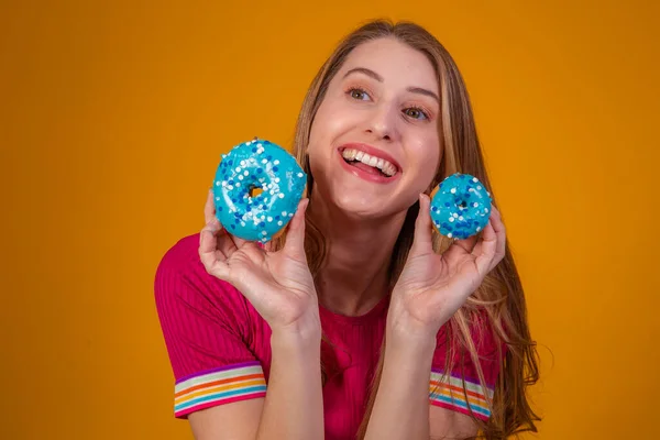 一个笑容满面的漂亮姑娘脸上挂着蓝色甜甜圈的画像 — 图库照片