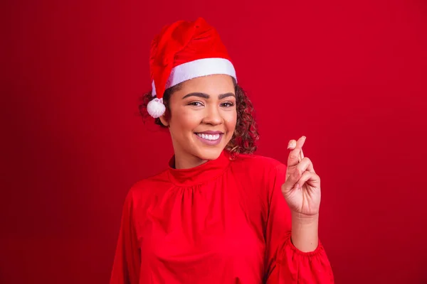 クリスマスの衣装の若い女性と指でサンタクラスの帽子は幸運を願って交差 — ストック写真