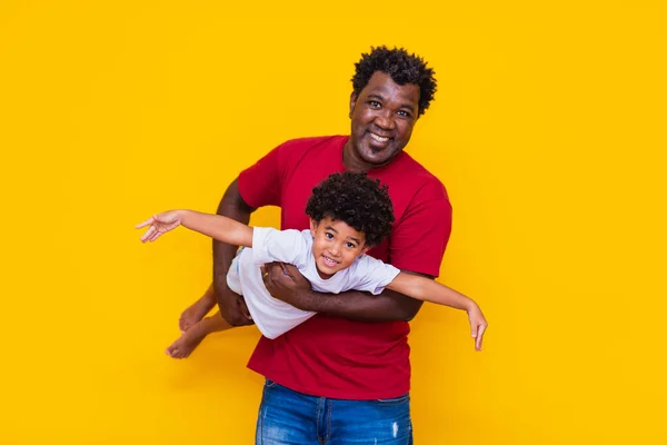 父亲和非洲裔儿子在黄色背景上笑着玩耍 父亲节的概念 — 图库照片