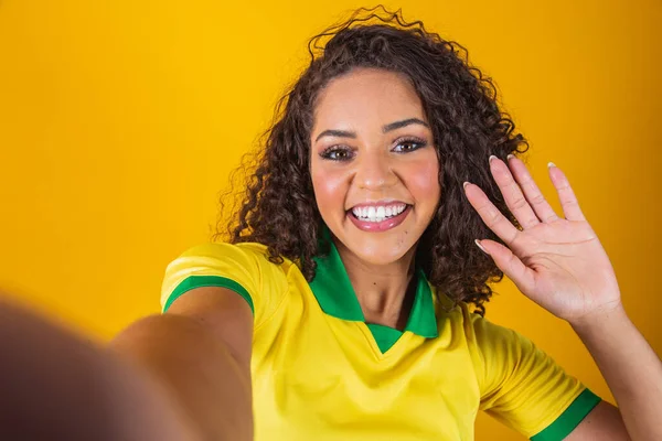 ブラジルのサポーター サッカーを祝うブラジルの女性ファン 黄色の背景にサッカーの試合 ブラジル色 セルフィースマートフォン — ストック写真