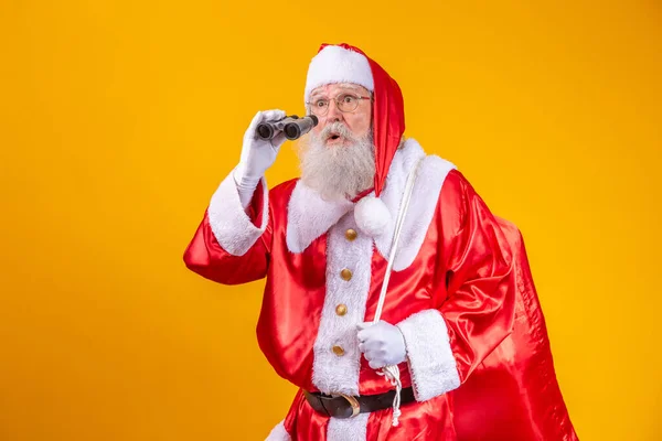 Studio Skott Santa Claus Tittar Igenom Kikare Isolerad Gul Bakgrund — Stockfoto