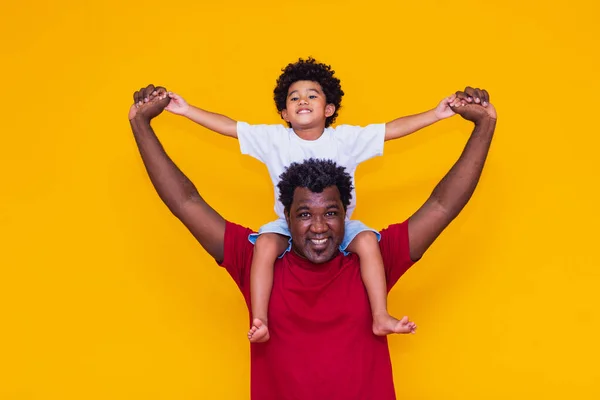 父亲和非洲裔儿子在黄色背景上笑着玩耍 父亲节的概念 — 图库照片