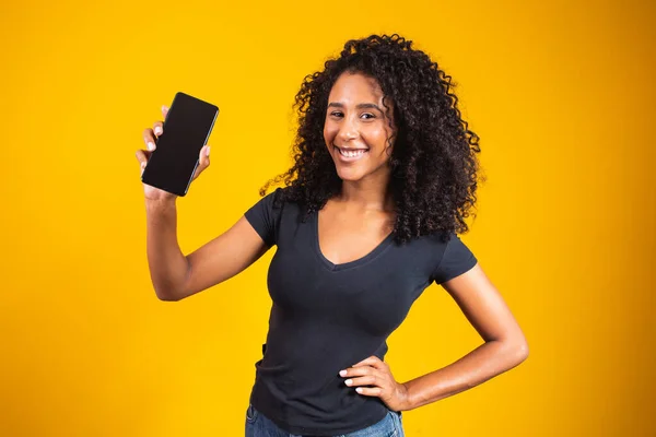 Sarı Arka Planda Boş Cep Telefonu Tutan Afro Saçlı Mutlu — Stok fotoğraf
