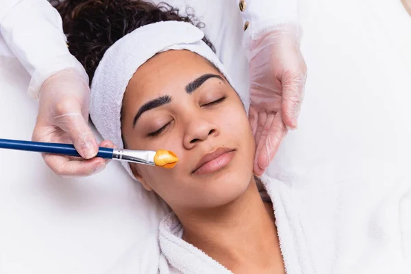 女人躺在美容师的办公室里进行脸部保湿 美容师在病人的脸上涂上保湿面膜 — 图库照片