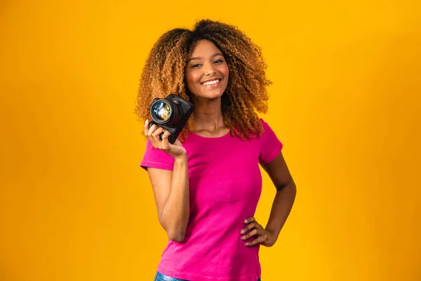 Młody Fotograf Afro Trzymając Kamerę Dłoniach Żółtym Tle — Zdjęcie stockowe
