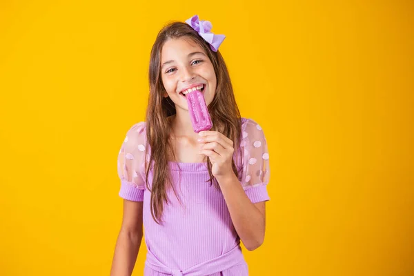 冷凍ポプシクルを食べる少女 愛らしいです女の子とともにおいしいですアイスクリームとともに色の背景 — ストック写真