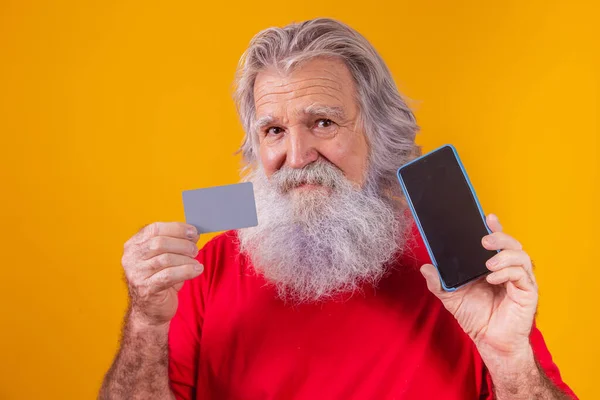 一个英俊的圣诞老人手持信用卡和智能手机 手里拿着空白屏幕的画像 — 图库照片