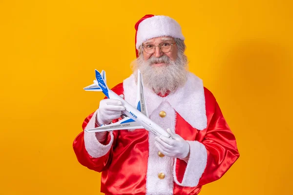 Santa Claus Sostiene Pequeño Avión Juguete Sobre Fondo Amarillo Concepto — Foto de Stock