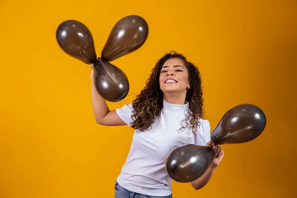 Afro woman with black balloons celebrating birthday offers. Black Friday sales