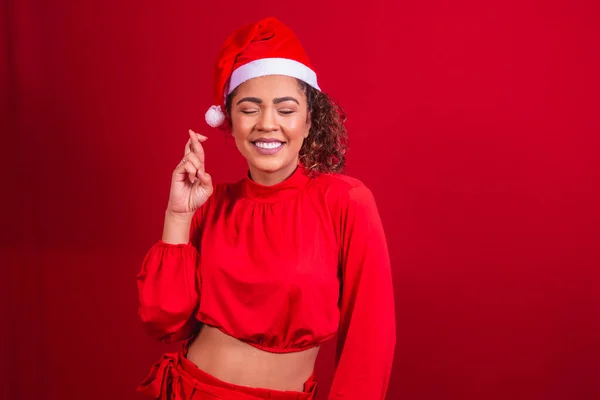 クリスマスの衣装の若い女性と指でサンタクラスの帽子は幸運を願って交差 — ストック写真