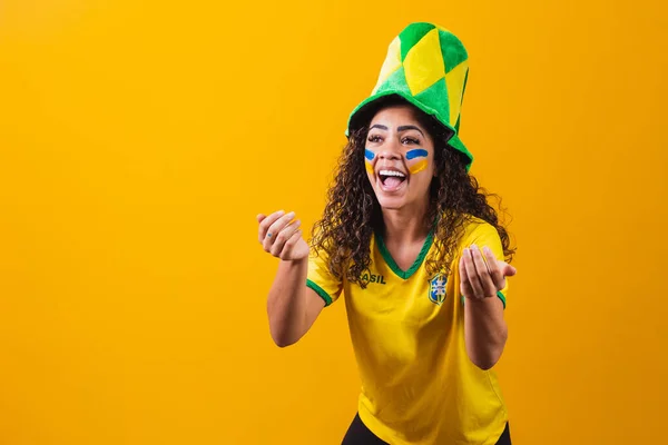 Brazilian fan. using paint as makeup, Brazilian fan celebrating football or soccer game on yellow background. Colors of Brazil.