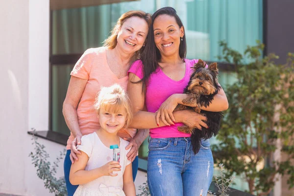 带着孩子和宠物狗笑同性恋夫妇 与收养女儿在一起的女同性恋夫妇 收养概念 — 图库照片
