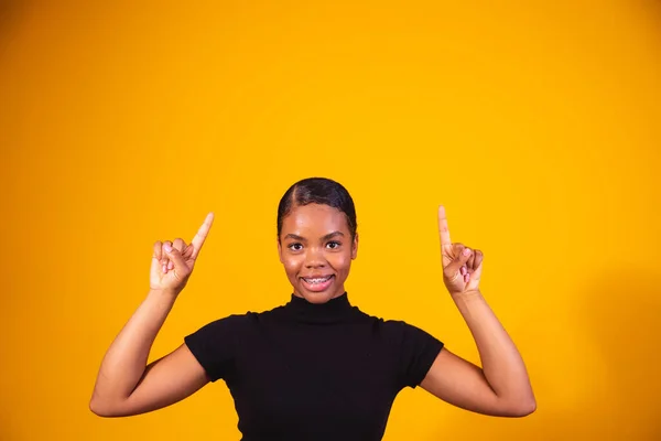 Close Mulher Afro Sorrindo Fundo Amarelo Apontando Para Cima Espaço — Fotografia de Stock
