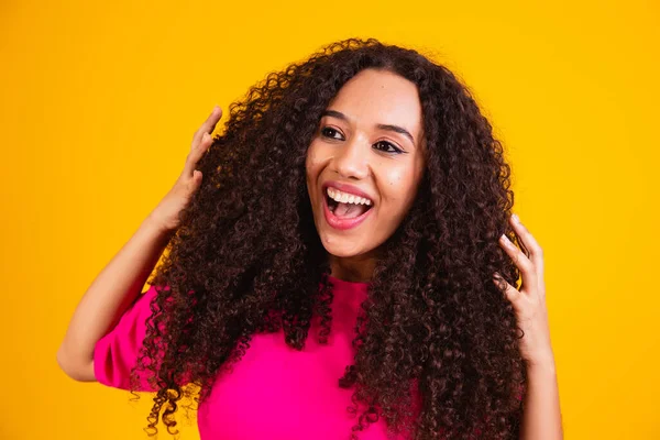 Beauty portrait of african american woman with afro hairstyle and glamour makeup. Brazilian woman. Mixed race. Curly hair. Hair style. Yellow background