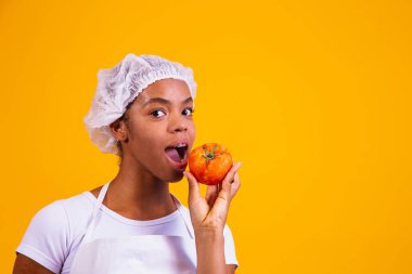 Önlüklü kadın elinde domates tutuyor. Domates tarifleri