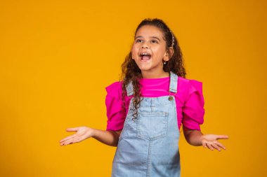Sarı arka planda ağzı açık duran heyecanlı küçük bir kız resmi..
