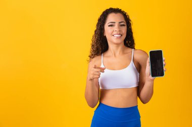 Spor uygulaması. Akıllı telefonu tutan ve gösteren heyecanlı genç adamın portresi, mesaj için boş bir ekranı işaret ediyor ve işaret ediyor.