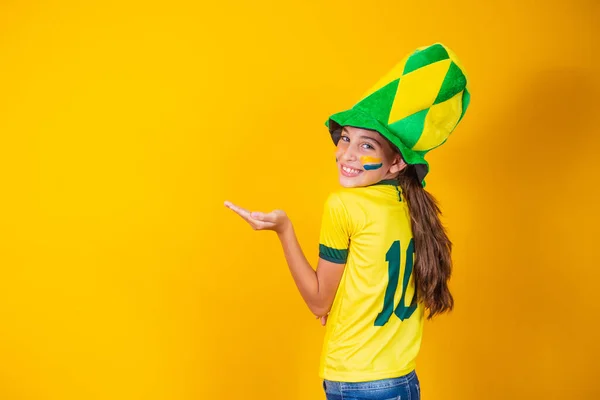 ブラジルのシャツを着て黄色の背景をした小さなブラジル人のファンの女の子 — ストック写真