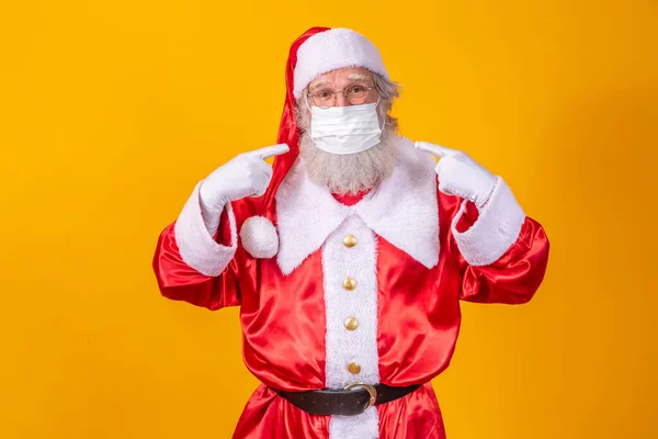 真正的圣诞老人 背景是黄色的 戴着保护面具 戴着眼镜和帽子 有社交距离的圣诞节 Covid — 图库照片
