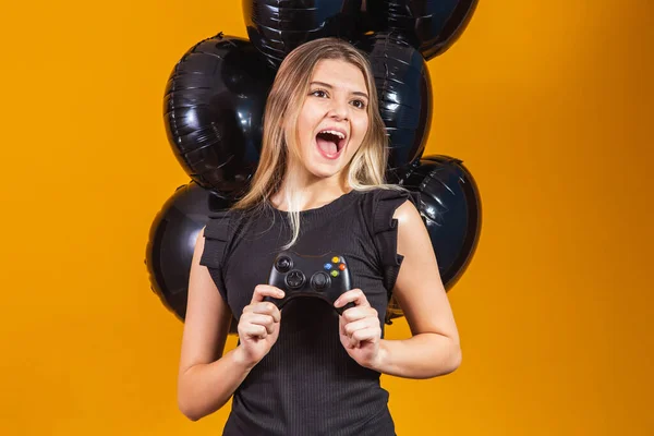 stock image Promotion of black friday in electronics. Young girl holding a video game controller on yellow background. Young man playing video game concept