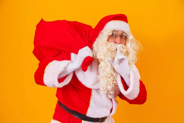 黄色背景的圣诞老人背着礼物提着袋子 圣诞老人在平安夜做了个惊喜 — 图库照片