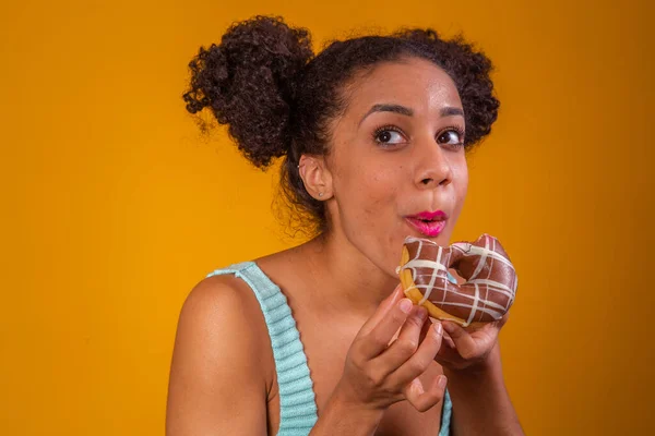 年轻的非洲女人吃美味的巧克力甜甜圈 — 图库照片