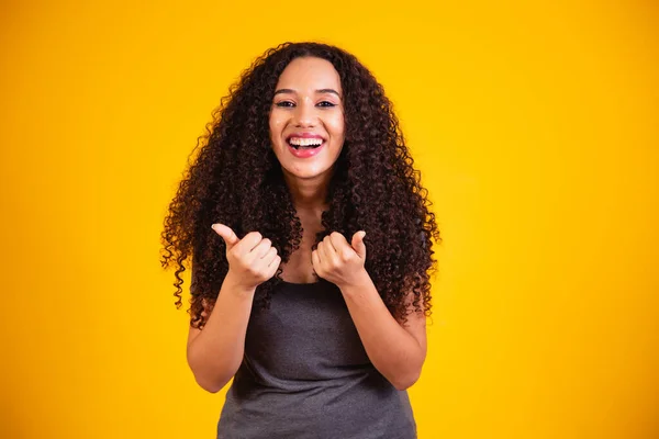 美丽的非洲裔美国女人 卷曲的头发 用她的手做着一个快乐的竖起大拇指的手势 看着成功镜头的认可表情 — 图库照片