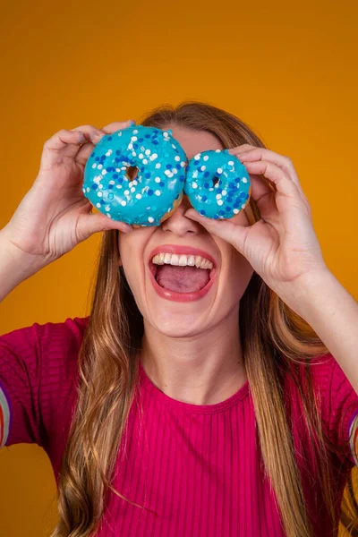 一个笑容满面的漂亮姑娘脸上挂着蓝色甜甜圈的画像 — 图库照片