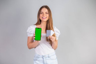 Sarışın Brezilyalı kadın akıllı telefon ve kredi kartı gösteriyor..