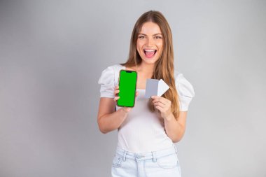 Sarışın Brezilyalı kadın akıllı telefon ve kredi kartı gösteriyor..